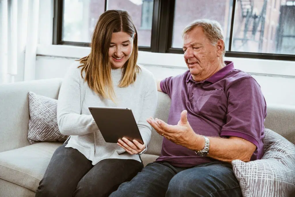 Une femme et un homme souriants échangent autour d’une tablette dans un cadre familial