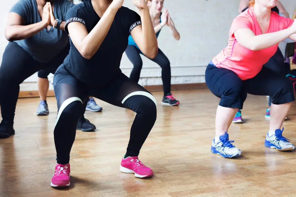 Groupe de personnes en mouvement lors d’un cours collectif de fitness en salle.