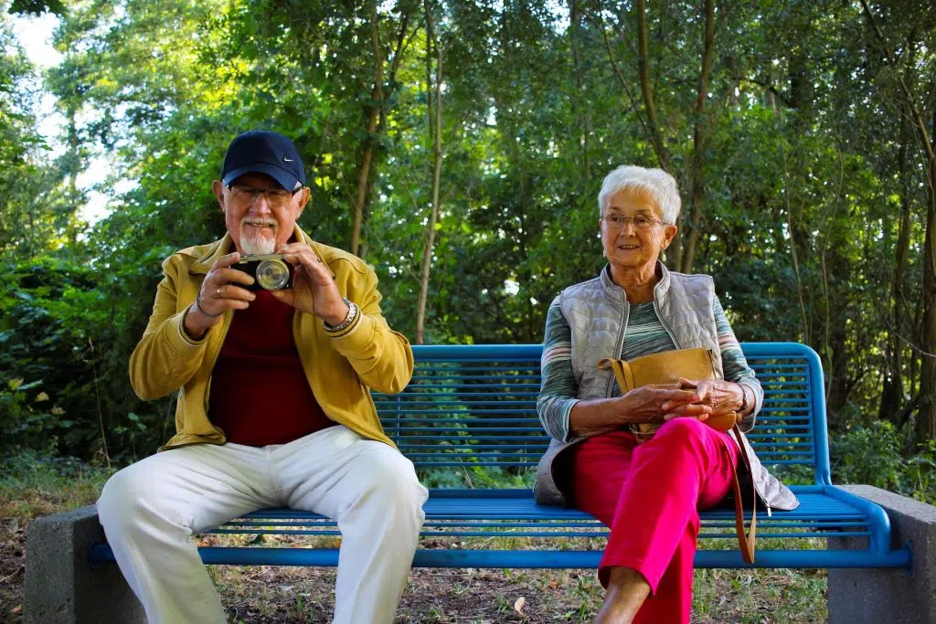 Couple senior assis sur un banc, prenant une collation ensemble
