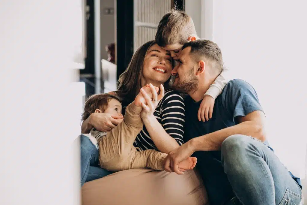 Une vie sain et équilibré pour le diabèt Jeune famille souriante enlacée dans leur salon, représentant un quotidien heureux malgré le diabète de type 1 ou 2