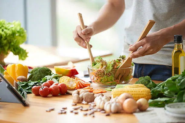 Une personne en train de cuisiner des légumes frais, représentant un guide simple et concret pour mieux manger avec plaisir