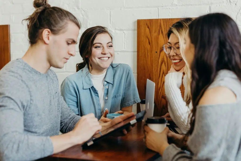 Réunion d’équipe souriante autour d’un projet avec ordinateurs et café