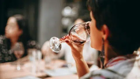 Femme en train de boire un verre de vin lors d’un dîner festif, illustrant la question de la consommation d’alcool chez les personnes diabétiques.