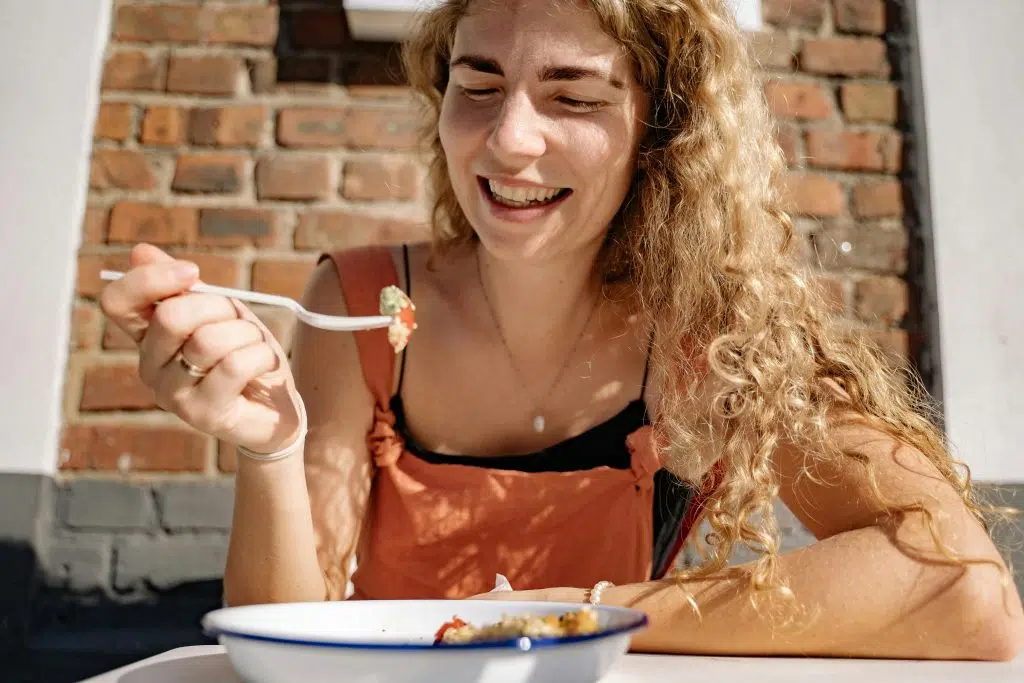 Femme souriante mangeant un repas équilibré à l’extérieur, illustrant une alimentation adaptée au diabète de type 2