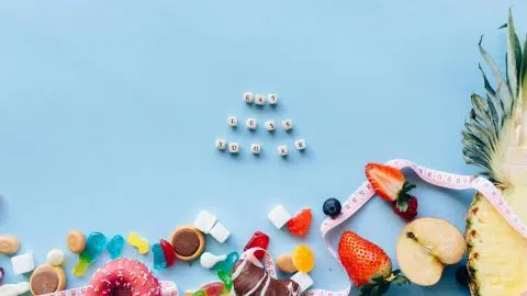 Image de sucreries et fruits encadrés par un ruban de mesure avec le message "Eat Less Sugar", illustrant les idées reçues sur le sucre et le diabète.