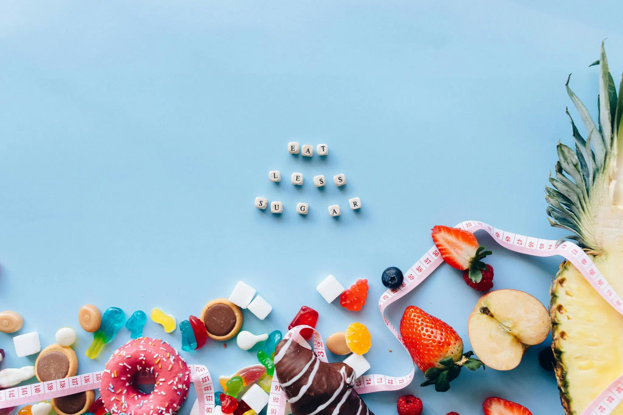 Image de sucreries et fruits encadrés par un ruban de mesure avec le message "Eat Less Sugar", illustrant les idées reçues sur le sucre et le diabète.
